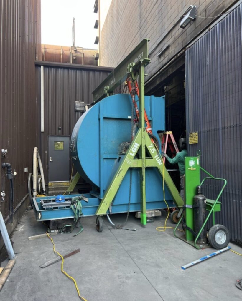 A steel gantry crane rental from LGH lifting a heavy industrial load.