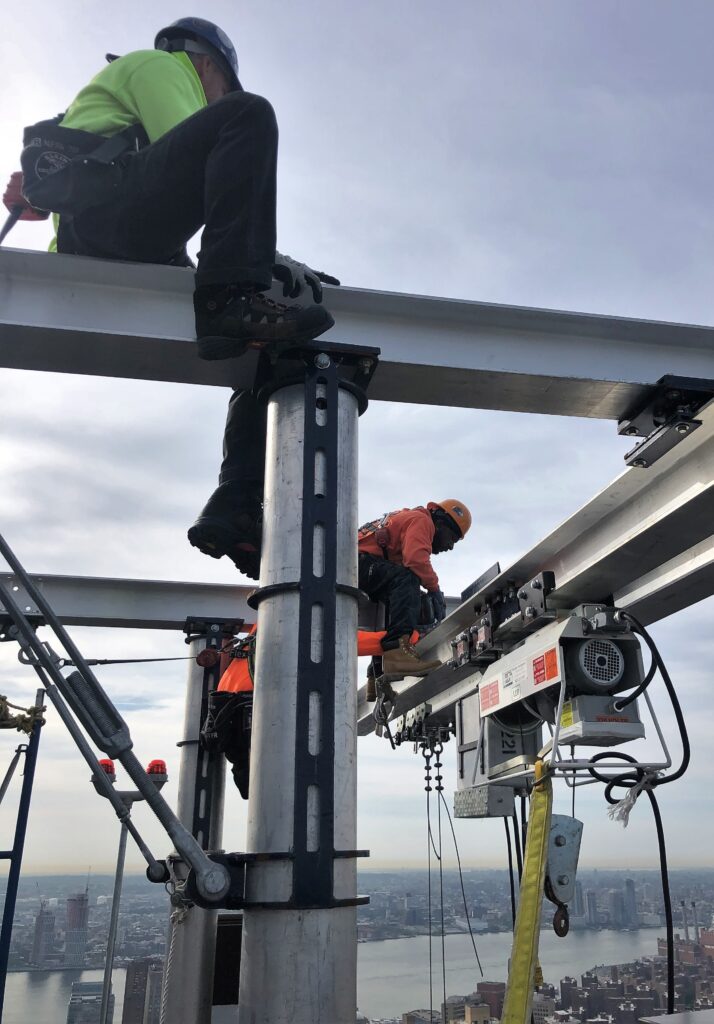 A jobsite photo of workers on top of a skyscraper building, using a Beta Max hoist rental from LGH.