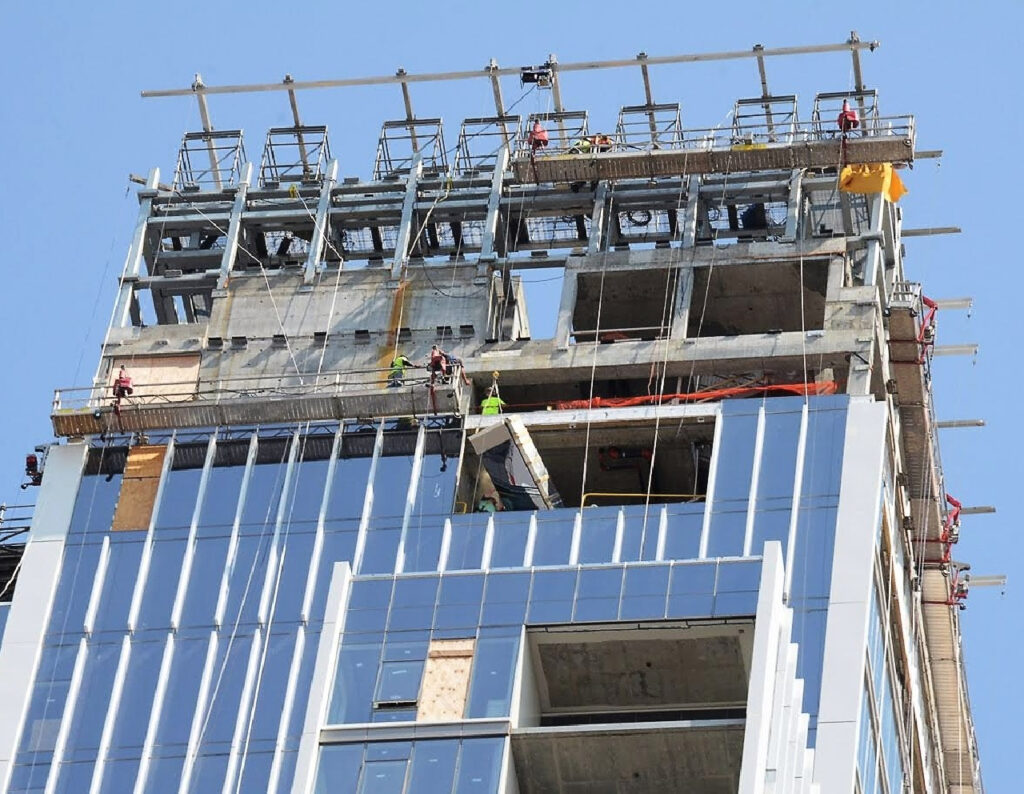 Jobsite photo of BETA MAX hoist lifting a load vertically up the side of a building.