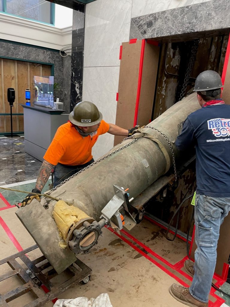 workers lowering a chiller component down an elevator shaft