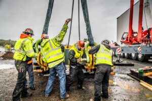 Riggers rigging up a load on a jobsite in safety gear.